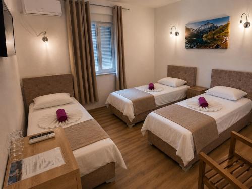 a hotel room with two beds with purple flowers on them at Rooms & Spa BJELASICA in Bijelo Polje