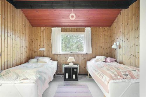 two beds in a room with wooden walls and a window at LN76740-Hjorring-Sostjernevej-11 in Hjørring