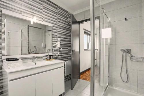ein Badezimmer mit Dusche, Waschbecken und einer Duschkabine aus Glas in der Unterkunft Cantinho Do Préstimo in Águeda