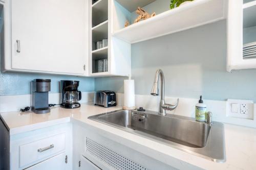a kitchen with a stainless steel sink and white cabinets at Oceanfront unit, Private Balcony, Beach Access, Sunset Views in Carlsbad