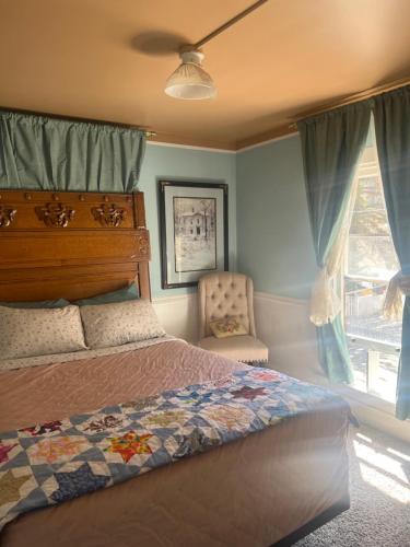 a bedroom with a bed and a chair and a window at Historic Windsor in Silver Plume