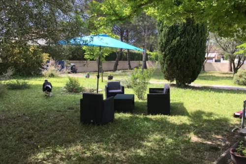a group of chairs and an umbrella in the grass at Maison avec jardin & proche plages in Saint-Jean-de-Védas