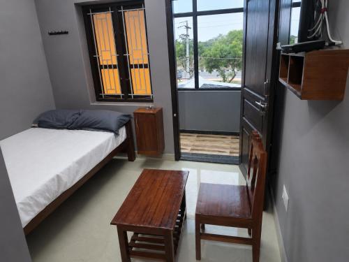 a bedroom with a bed and a table and a window at Hotel Sabareesh Kanyakumari in Golden Rock
