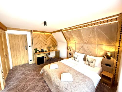 a hotel room with a large bed and a desk at Willa Regina II Resort & SPA in Zakopane
