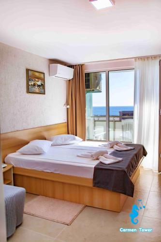 a bedroom with a large bed with a view of the ocean at Hotel Carmen Tower - Balada in Saturn