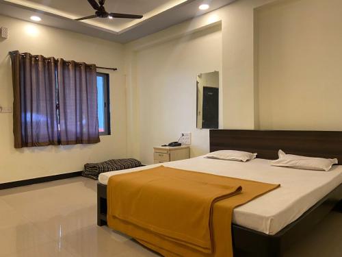 a bedroom with a large bed with a yellow blanket on it at Shree Krishna Sudha Resort in Alibaug