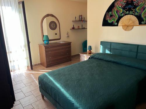 a bedroom with a green bed and a mirror at MAREMONTI alloggio turistico in Formia