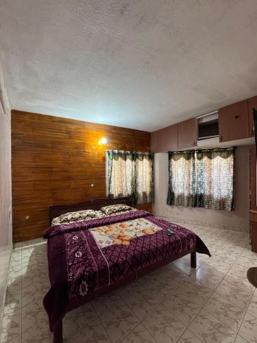 a bedroom with a bed in a room with windows at DD cottages in Ooty
