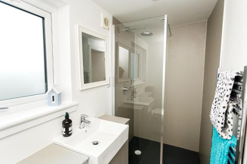 a white bathroom with a sink and a shower at Jack's Hideaway in Gatehouse of Fleet