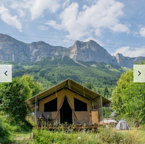 a tent in a field with mountains in the background at Camping Onlycamp Les Petites Roches in Saint-Hilaire