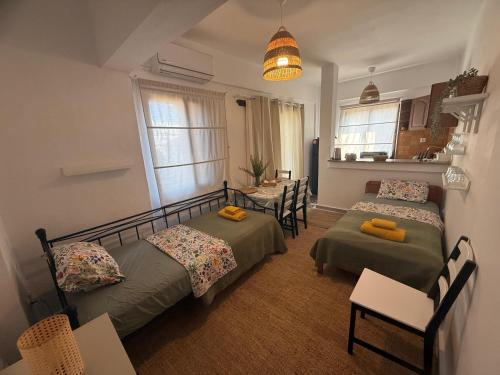 a bedroom with two beds and a table and a kitchen at Azure & Zest Suites in Ierissos