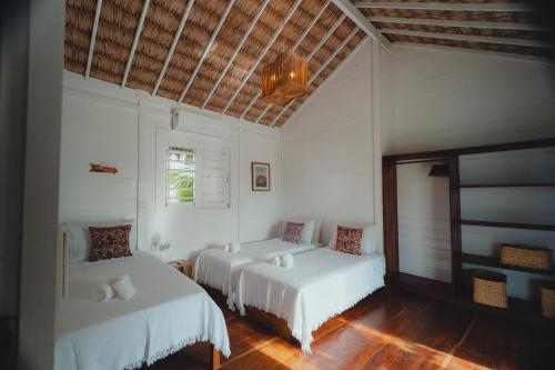 two beds in a room with white walls and wood floors at Villa Tomama by Preabeach Experience in Prea