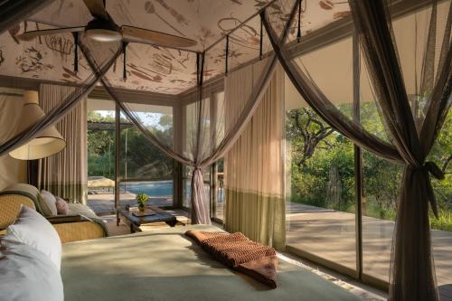 a bedroom with a bed and a large window at Saseka Tented Camp in Hoedspruit