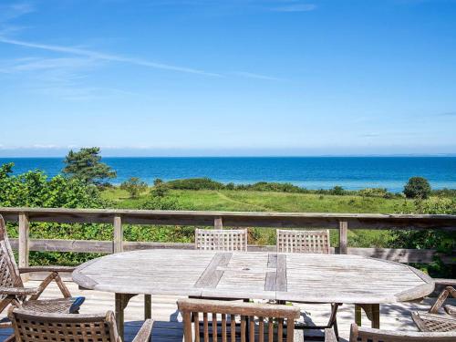 a wooden table and chairs on a deck with the ocean at 8 person holiday home in Asnæs in Asnæs