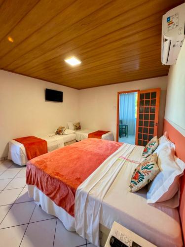 a hotel room with two beds and a tv at Pousada Mirante das Fitas in Arraial d'Ajuda