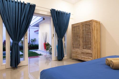 a bedroom with blue curtains and a bed and a dresser at Villa Casablanco in Seminyak
