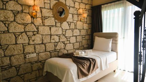 a bedroom with a bed and a stone wall at Canata Çeşme in Çeşme