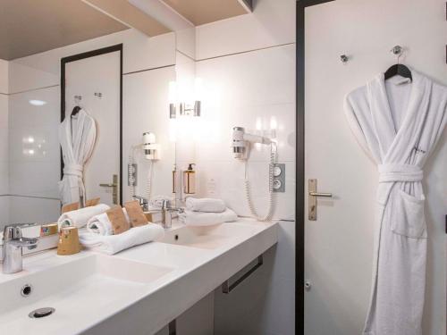 a white bathroom with two sinks and a mirror at Mercure Granville Le Grand Large in Granville