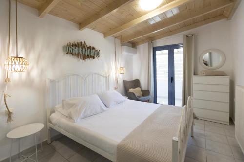 a white bedroom with a white bed and a chair at Nikolas Apartments in Amoudara Herakliou