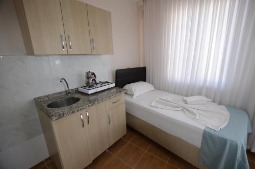 a small bathroom with a bed and a sink at Cane Motel in Avşa Adası