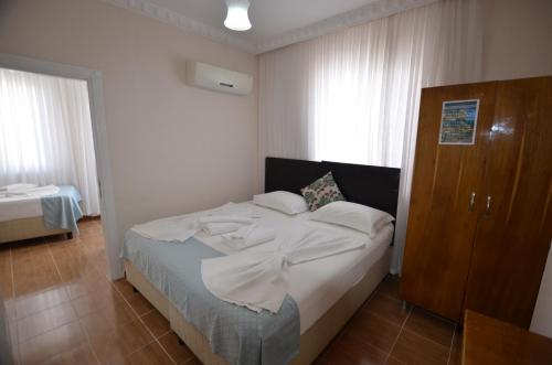 a bedroom with a bed with white sheets at Cane Motel in Avşa Adası