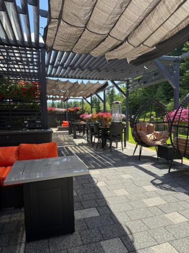 a patio with tables and chairs under a pergola at Hotel Jakuszyce Sport & Spa in Szklarska Poręba