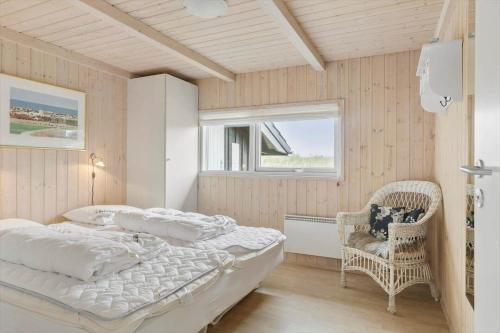 a bedroom with a bed and a chair and a window at LN1954-Hirtshals-Harestien-27 in Hirtshals