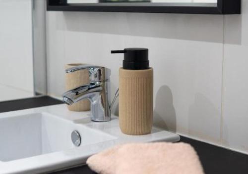a bottle of soap sitting on top of a sink at Doux Pavillon - Sauna - Jacuzzi in Tassin-la-Demi-Lune