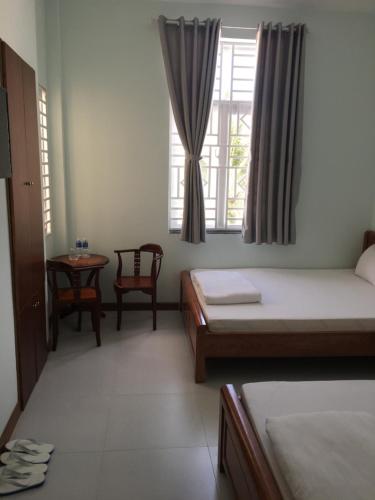 1 dormitorio con 2 camas, mesa y ventana en Khách Sạn Đào Nguyên, en Tuy Phong