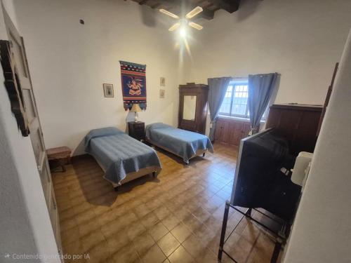 a living room with two beds and a television at La Casa de Lalo in Cafayate