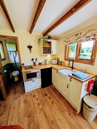 a kitchen with white cabinets and wooden floors at Lintmill Lodges - Heather Shepherds Hut in Sorn