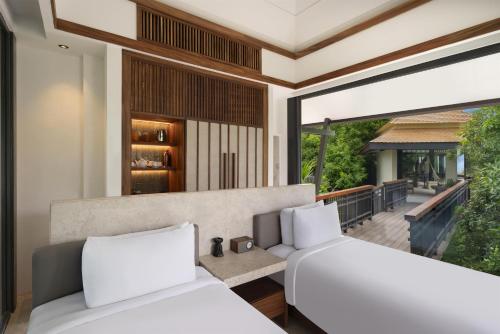 two beds in a bedroom with a balcony at Banyan Tree Cabo Marques in Acapulco