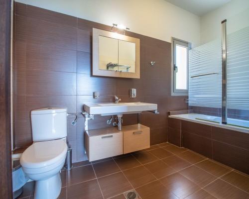 a bathroom with a toilet and a sink and a tub at Villa Ilias in Skala