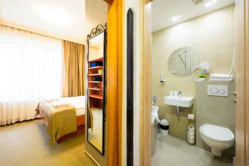 a bathroom with a bed and a toilet and a sink at Hotel Roudna in Pilsen