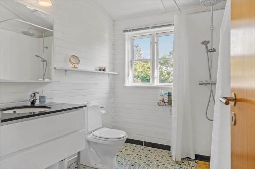 a bathroom with a toilet and a sink and a window at LN1987-Hjorring-Havbruset-6 in Hjørring