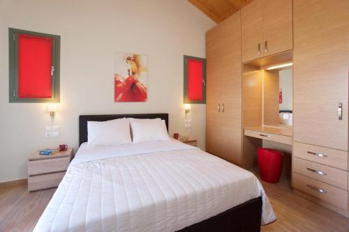 a bedroom with a large white bed and wooden cabinets at Trapezaki Queen Villa in Trapezaki