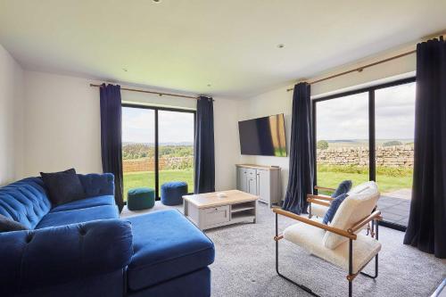 a living room with a blue couch and chairs and windows at Host & Stay - Thistle Cottage in Rochester