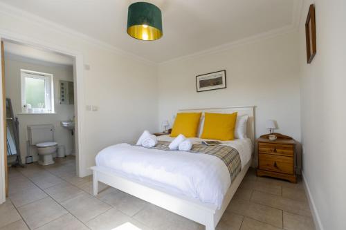 a bedroom with a white bed with yellow pillows at The Dutch Barn in Stratton Audley