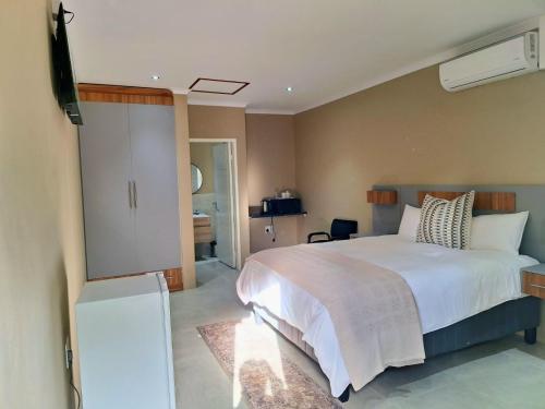 a bedroom with a white bed and a television at 49 Sannaspos in Bloemfontein