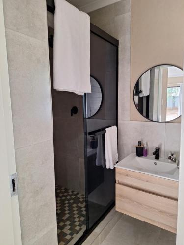 a bathroom with a sink and a shower with a mirror at 49 Sannaspos in Bloemfontein