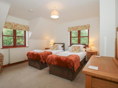 two beds in a room with two windows at Byne Brook Cottage in Wistanstow