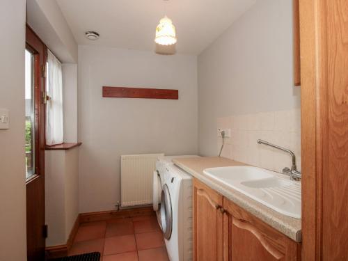 a laundry room with a sink and a washing machine at Byne Brook Cottage in Wistanstow