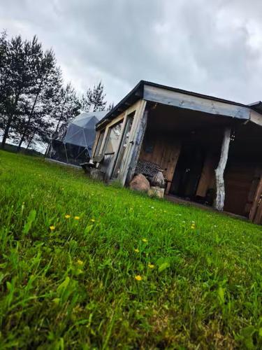 a building sitting on top of a lush green field at Kupolinis namelis Miško Pašvaistėje in Balneliškiai