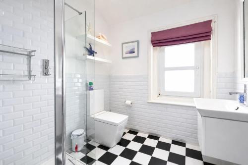 a white bathroom with a toilet and a sink at Driftwood Cottage by Bloom Stays in Folkestone