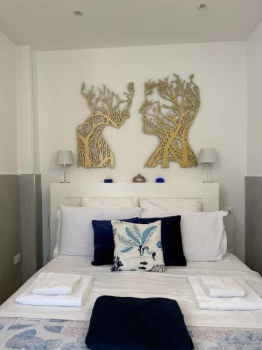 a bedroom with a large white bed with two paintings on the wall at Tourist House Bologna - Self check-in in Bologna