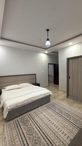 a bedroom with a large bed and a rug at v2 غرفة وصالة in Al Wajh