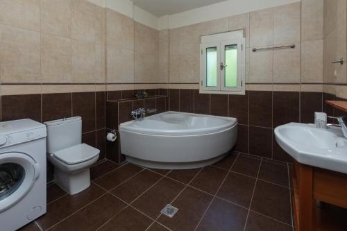 a bathroom with a tub and a toilet and a sink at Lourdas Beach View by Villa Select in Lourdata