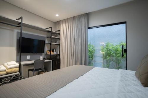 ein Schlafzimmer mit Bett, Schreibtisch und einem großen Fenster in der Unterkunft Duna Queen Hotel Conceito in Barreirinhas