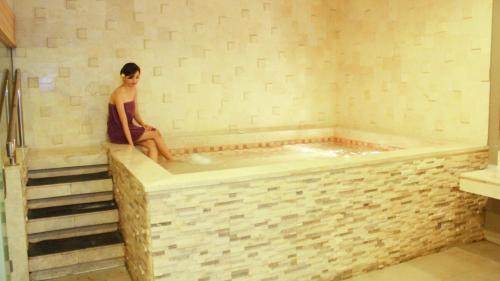 a woman sitting in a tub in a bathroom at Holiday Inn Bandung Pasteur by IHG in Bandung