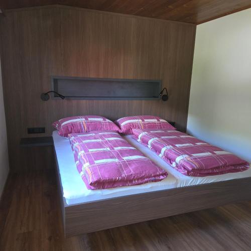 a bed with pink pillows on it in a room at Merlschober, Ferienwohnung 8, Ossiacher See in Ossiach